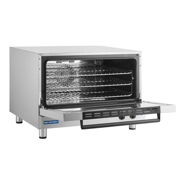 A stainless steel countertop convection oven with an open front door and three wire racks inside.