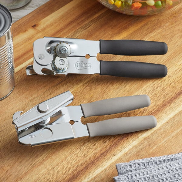 A Choice manual can opener with black handles on a wooden surface.