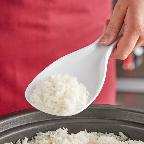 A person using an Avantco rice paddle to serve rice from a bowl.