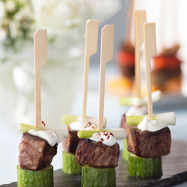 A piece of meat and a green vegetable on a bamboo skewer.