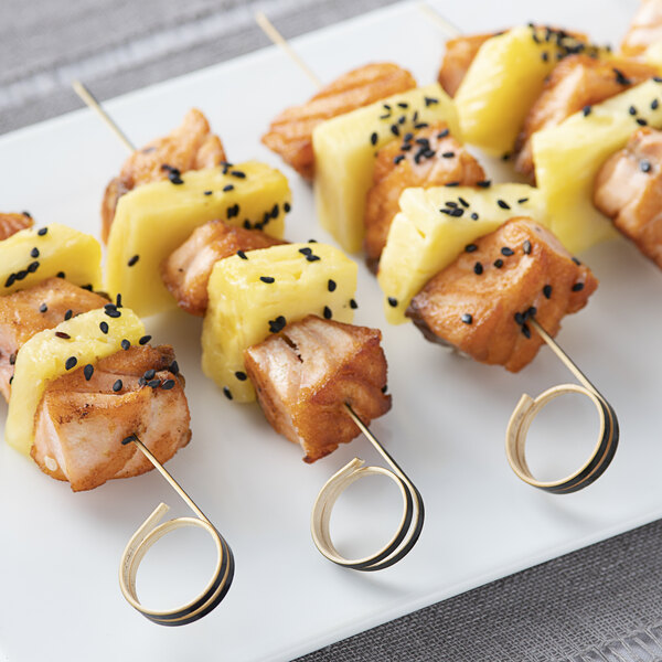 Bamboo skewers with sushi and chicken on a plate.