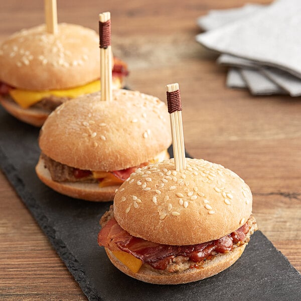 Three hamburgers on a table with Bamboo by EcoChoice trident skewers.