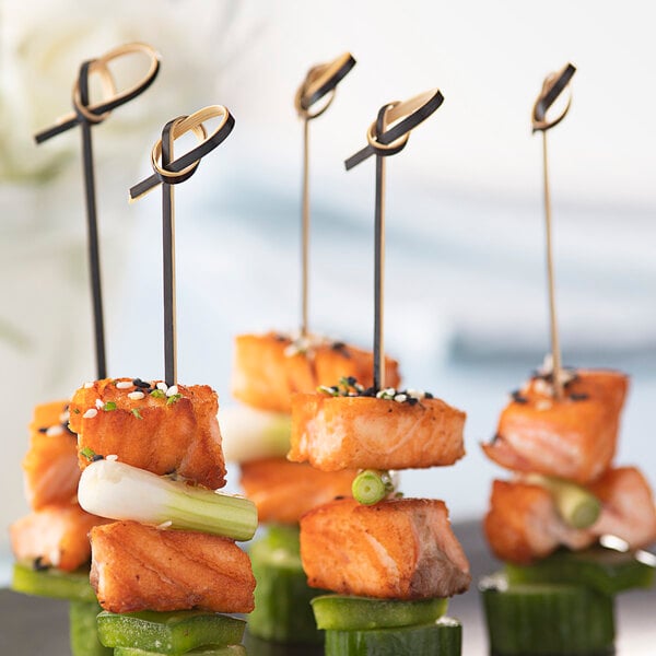 Bamboo skewers with salmon, cucumber, and celery on a table.
