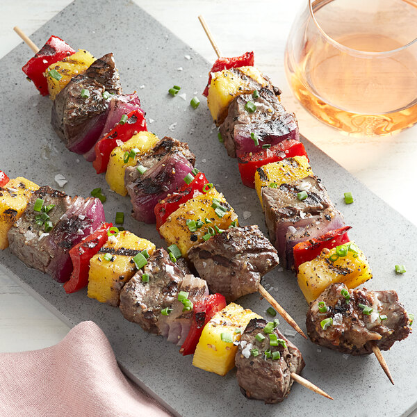 EcoChoice wooden skewers with grilled beef and pineapple on a grey plate.