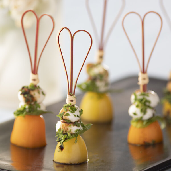 A black tray of Bamboo by EcoChoice heart food picks skewered into appetizers.