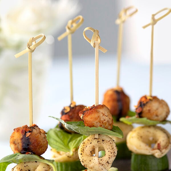 A plate with appetizers on Bamboo by EcoChoice bamboo knot food picks on a table at a catering event.