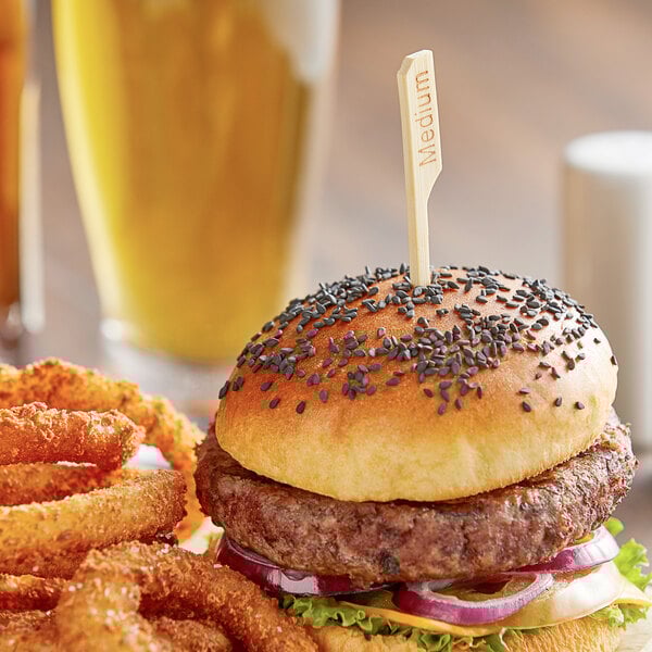 A burger and onion rings with a Bamboo by EcoChoice meat marker on a table.