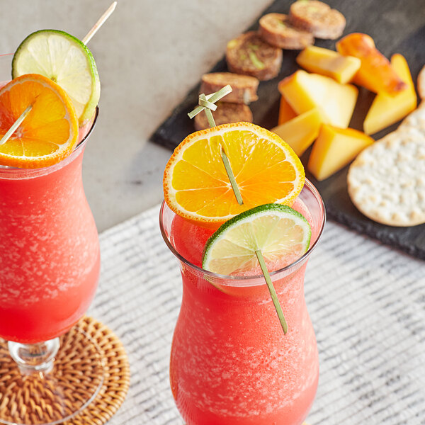 Two glasses of drinks with fruit and Bamboo by EcoChoice bamboo skewers with orange slices on a table in a cocktail bar.