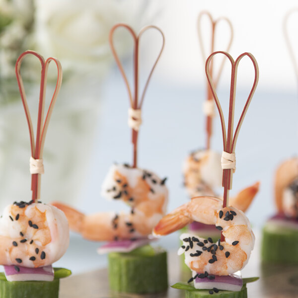Bamboo heart skewers holding shrimp and cucumber on a platter.