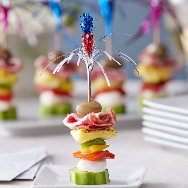 A plate of food with Choice sparkler food picks on a table.