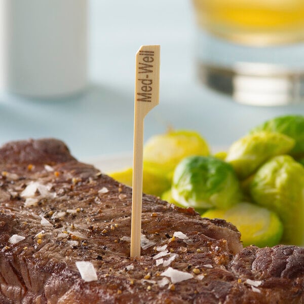 A piece of meat with a Bamboo "Medium Well" Meat Marker in the middle of it.