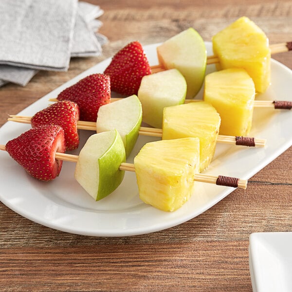 A plate of fruit skewers with apples, pineapples, and strawberries.