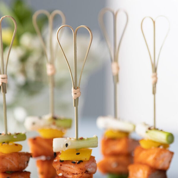 A bunch of EcoChoice bamboo heart food picks on a table with food on them.