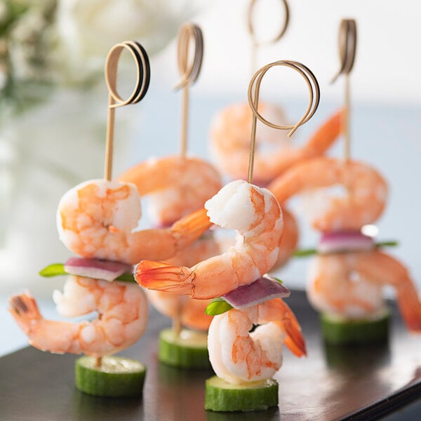 Bamboo skewers with shrimp and vegetables on a plate.