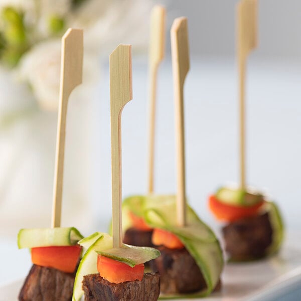 A plate of food skewered on green bamboo sticks.