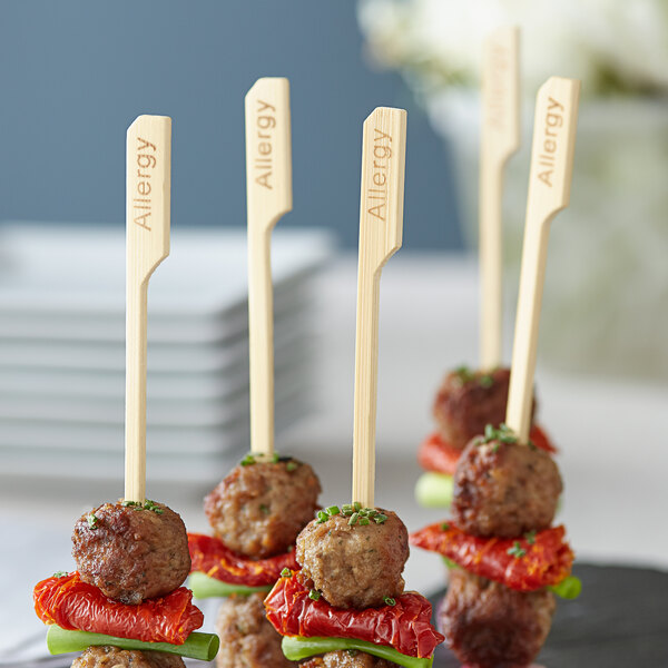 Bamboo food picks with meatballs on a plate.