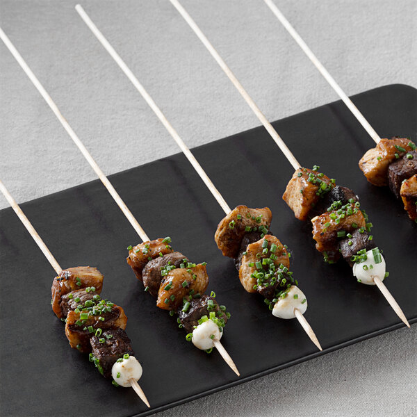 A plate of food with meat and green onions on EcoChoice wooden skewers.
