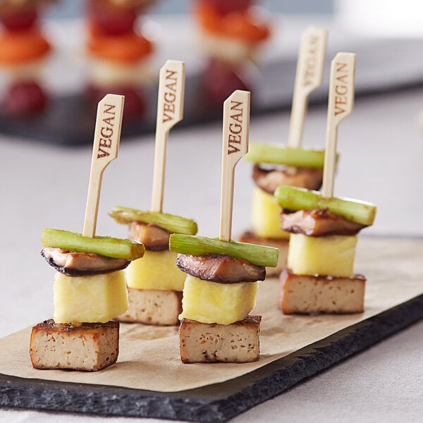 A group of vegan appetizers on a plate with bamboo food picks.