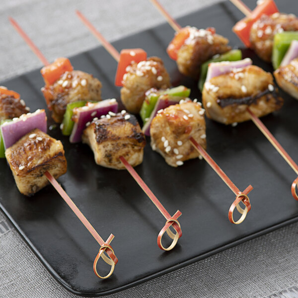 Bamboo skewers with chicken, vegetables, and peppers on a plate.