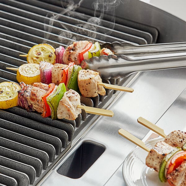 Bamboo skewers of food on a grill.