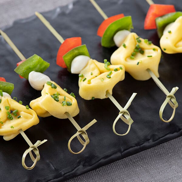 A black plate of food skewered with Bamboo by EcoChoice bamboo skewers.