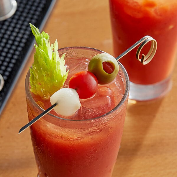 A glass of red liquid with a Bamboo Loop Skewer holding olives.