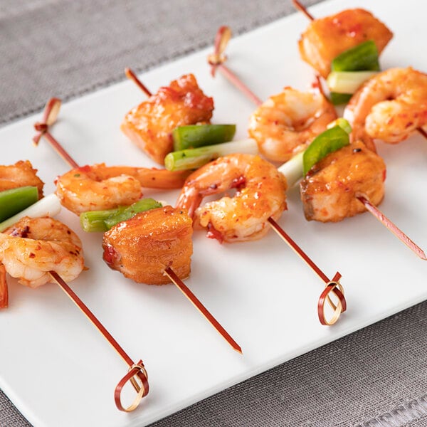 A Bamboo by EcoChoice shrimp skewer on a plate of food.