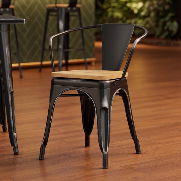 A Lancaster Table & Seating black metal arm chair with natural wood seat and back.