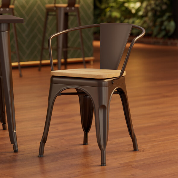 A Lancaster Table & Seating metal arm chair with a natural wood seat.