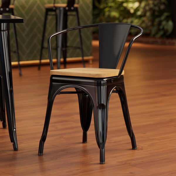 A Lancaster Table & Seating black metal arm chair with a natural wood seat and back.