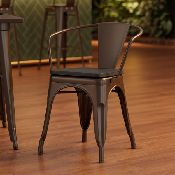 A Lancaster Table & Seating metal arm chair with black wood seat.