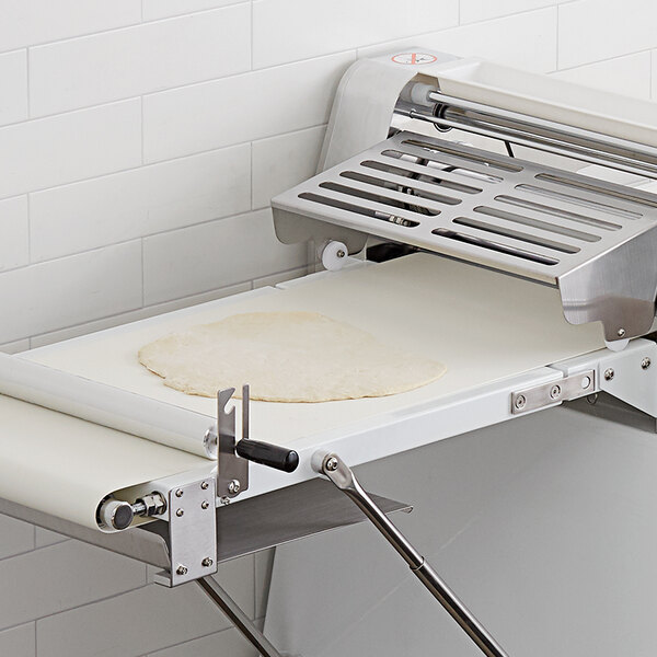 A white conveyor belt with dough on it.