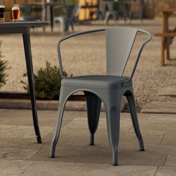 A Lancaster Table & Seating charcoal outdoor arm chair on a stone patio.