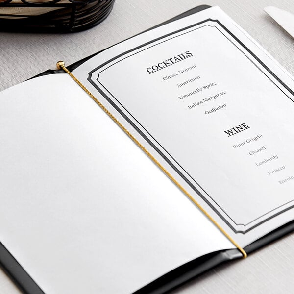 A white table with a menu held together with a gold elastic band.