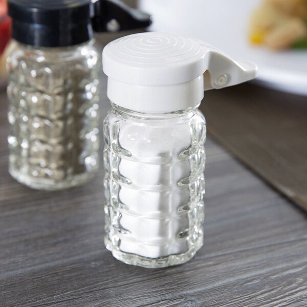 A Tablecraft glass salt shaker with a white lid.