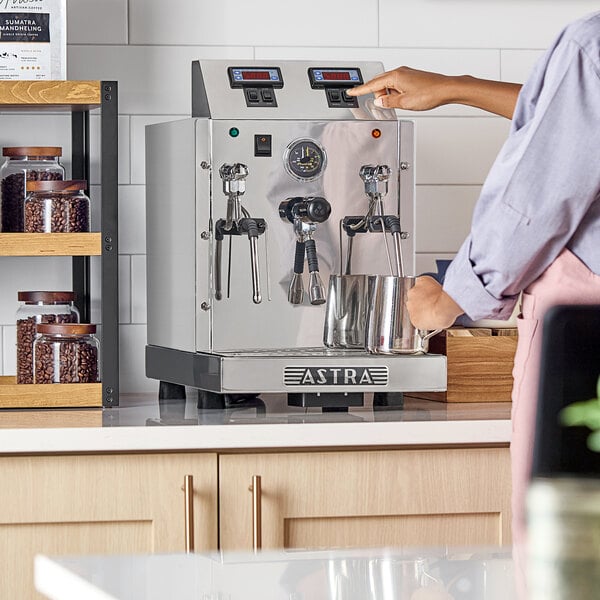 An Astra STA2400 automatic milk and beverage steamer with two wands on a countertop.