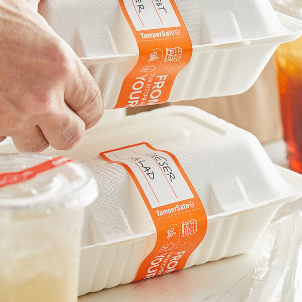 A person using a bumpy hand to apply a TamperSafe orange label to a white food container.