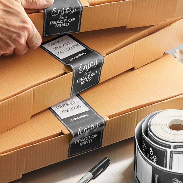 A hand using a black TamperSafe label to seal a package.