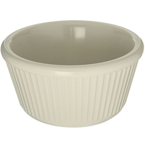 A Carlisle bone white fluted melamine ramekin with a ruffled edge.