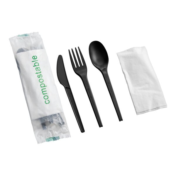 A compostable cutlery set including a black knife, fork, spoon, and a white napkin, all individually wrapped.