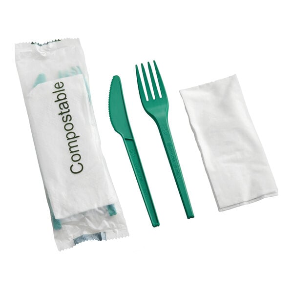 A set of green compostable plastic knife and fork with a white napkin, individually wrapped.