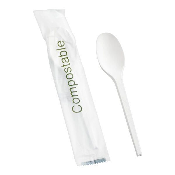 A white compostable heavy weight spoon and its individual wrapper labeled 'Compostable.'