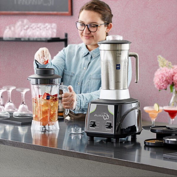 A woman using an AvaMix commercial blender to make a fruit smoothie.