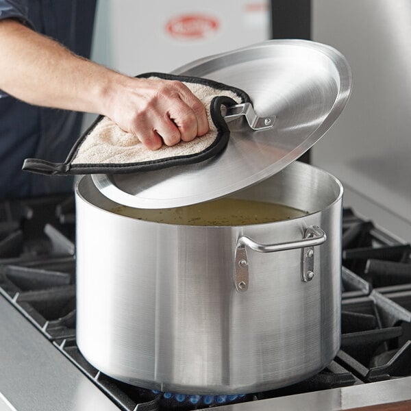 A person using a Choice aluminum sauce pot and lid to cook.