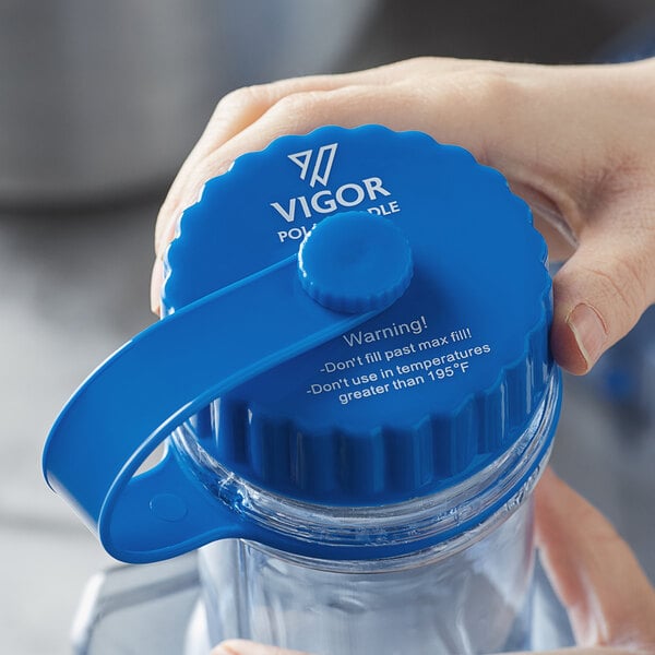 A hand holding a blue plastic circular cap.