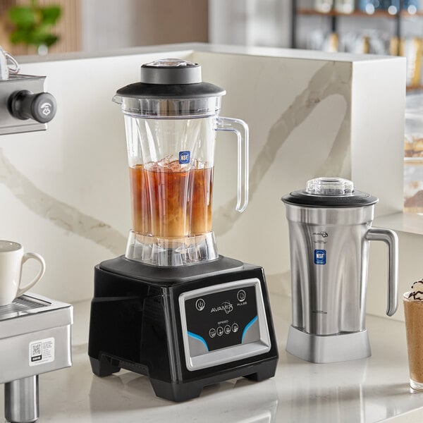 A commercial blender with a digital keypad control base, featuring a clear plastic jar filled with liquid and ice, and an additional stainless steel jar beside it.