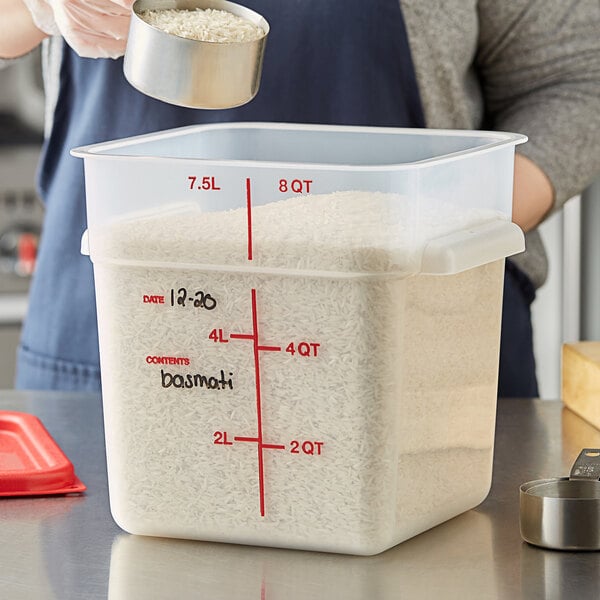 A woman using a Vigor 8 quart translucent square polypropylene food storage container to pour white rice.