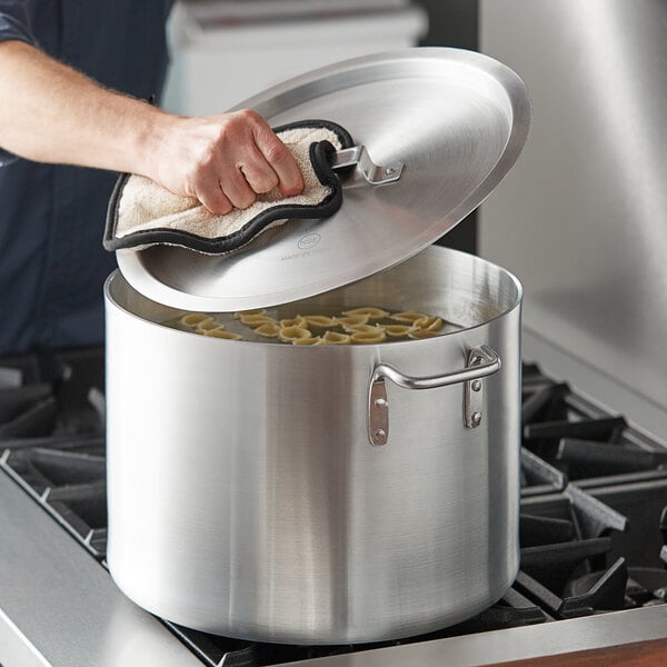 A person cooking pasta in a Choice aluminum sauce pot on a stove.