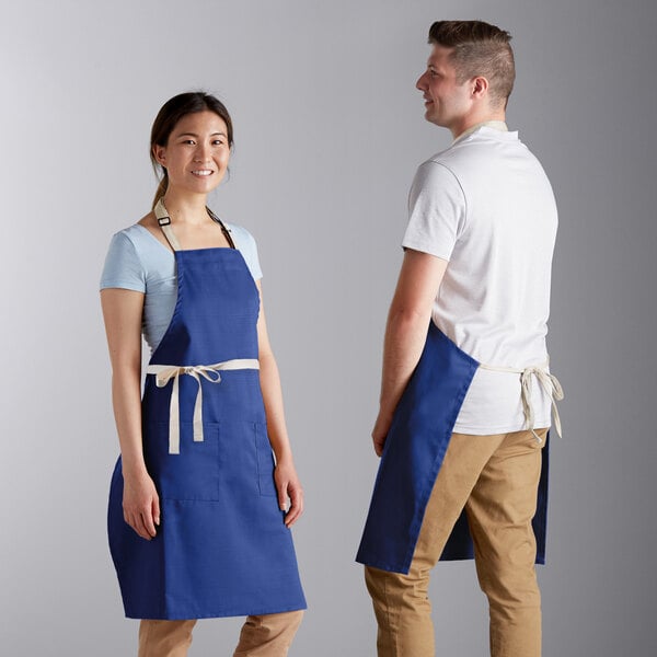 A man and woman wearing Choice royal blue aprons with natural webbing accents.