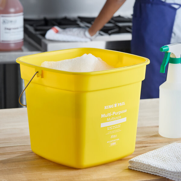A yellow Noble King-Pail 10 quart cleaning pail filled with soapy water.